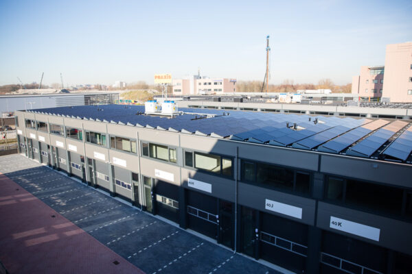 Bedrijfsverzamelgebouw aan de Laan van 's-Gravenmade met zonnepanelen op het dak en parkeervakken ervoor.